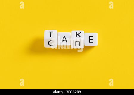 take care message spelled on white blocks on yellow background Stock Photo