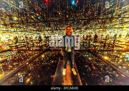 Angela Berg stands in the light installation ‘Infinity Mirror Room – Fireflies on the Water’ by the Japanese artist Yayoi Kusama at the Musée des Beaux-Arts de Nancy. Countless colourful points of light are endlessly reflected in the mirrored walls of the dark room. The museum received the work on loan from the Centre national des arts plastiques in 2001. Stock Photo