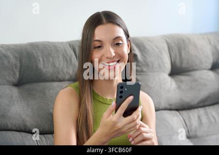 Happy Young Brazilian Woman Smiling and Feeling Satisfied Using New Mobile Banking App on her Smartphone Stock Photo