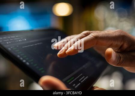 Engineer using tablet in startup office, optimizing code for performance and scalability, doing quality assurance. Close up of IT employee looking at Stock Photo