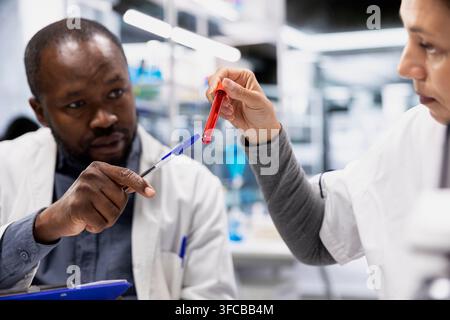 Team of scientists analyzing blood samples for hereditary disease markers. Teamworking laboratory coworkers doing research on sanguine fluid vials to Stock Photo