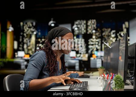 Stressed admin in startup office worried after noticing error in code while doing quality assurance. African american woman frantically pressing keybo Stock Photo