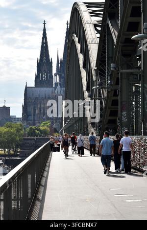People walking across the Hohenzollern Bridge towards Cologne Cathedral in Germany. Stock Photo