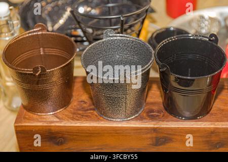 Three Small Empty Metal Buckets at Block of Wood Close up Stock Photo