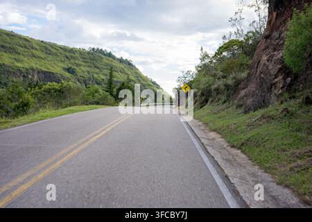 Winding asphalt road navigating through a scenic landscape of rolling green hills and rugged rock formations, offering a sense of exploration and the Stock Photo
