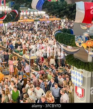 crowded traditional beer tent interior with garlands and festive decorations at oktoberfest in munich germany Stock Photo