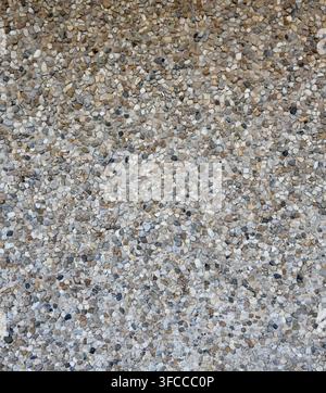 Vertical close up of decorative pebble embedded concrete pavement with smooth rounded multi color pebbles partially set into uneven concrete Stock Photo