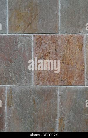 Close-up vertical view of precast cement square tiles with porous, rough uneven faces and evenly filled mortar joints Stock Photo
