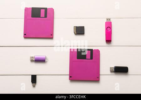 Evolution of data storage technology floppy disks usb flash drives and sd card on white wooden background Stock Photo