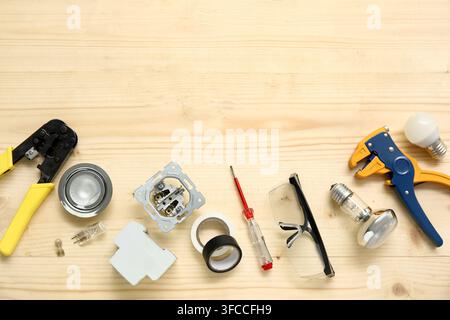 Electricians tools and light bulbs on wooden background Stock Photo
