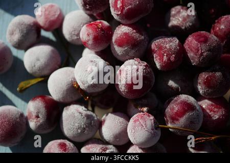 Frozen red cherries on a blue table in sunlight Stock Photo