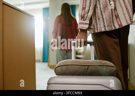 Man Holding Suitcase Handle While Entering Hotel Room with Woman Stock Photo