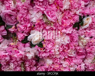 a decorative wall adorned with an elegant arrangement of artificial roses in shades of white and pink Stock Photo