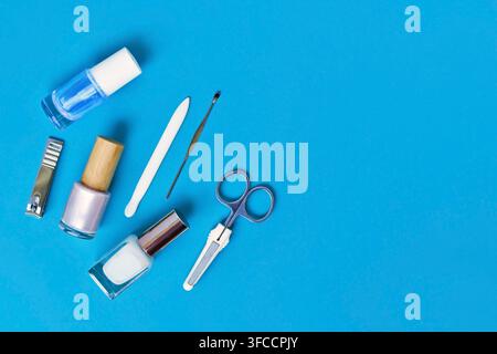 Manicure set and nail polish arranged on side of blue background with copy space Stock Photo