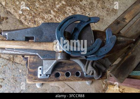 Farrier Hammer and Horseshoes Arranged on Traditional Anvil Stock Photo