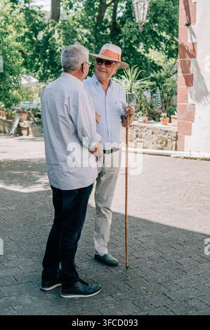 Two older men chatting outdoors in the grounds of a historic property in Wertheim, Baden-Württemberg, Germany. Stock Photo