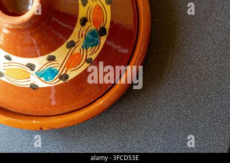 Top view of a hand painted glazed terracotta Moroccan tagine lid on a dark grey speckled stone surface with copy space Stock Photo