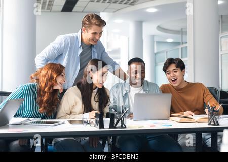 Brainstorm, Teamwork Concept. Smiling mixed race employees or students team watching webinar on laptop together, working with computer, looking at scr Stock Photo