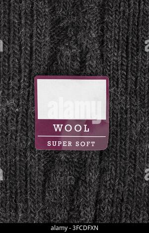 Clothes label text Wool Super Soft over black knit fabric background Stock Photo