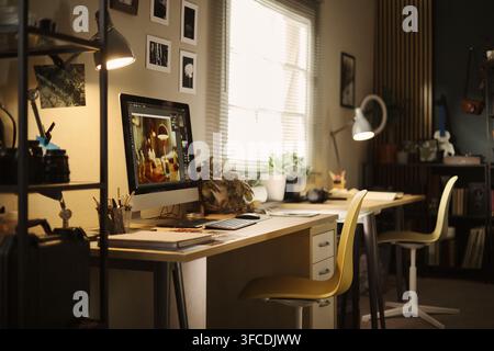 Empty creative home office workspace featuring computer monitor displaying photo editing software. Ideal for remote work, freelance graphic design, and digital marketing campaigns Stock Photo