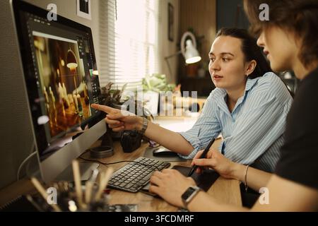 Couple of designers collaborating on photo editing project using computer and graphic tablet. Image suitable for creative agency and digital design school marketing Stock Photo