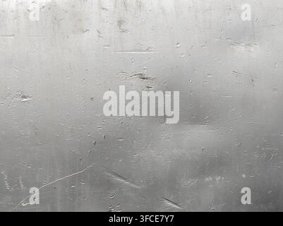 Close-up view of a textured silver aluminum metallic surface, showcasing scratches, scuffs, and dents. The uneven texture and variations in reflectivity create an abstract background, suggestive of wear and tear. Stock Photo