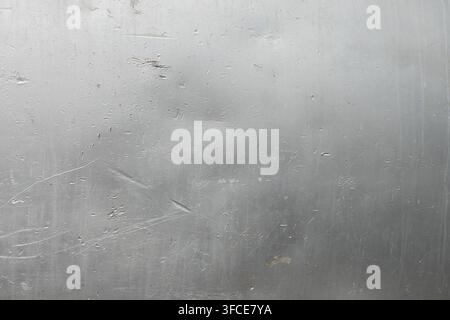 Detailed close-up of a brushed Aluminum metal surface showing scratches and smudges. Tiny water droplets create reflections, enhancing the texture and Stock Photo