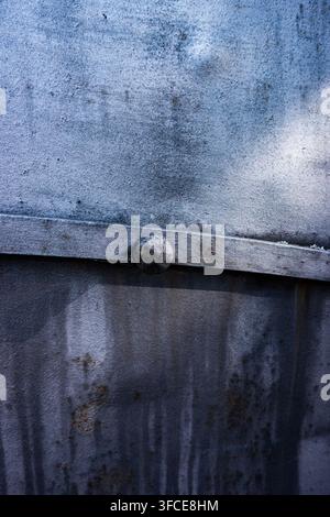 Close-up of weathered blue-grey metal panels with a round rivet, showing rust, scratches and industrial surface texture Stock Photo