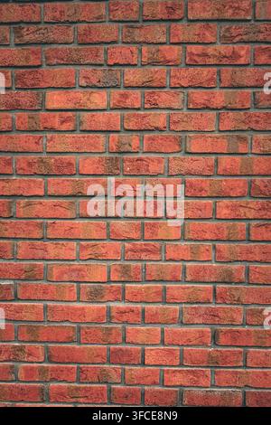 Full-frame red brick wall with varied handmade brick textures and dark mortar joints, forming a warm architectural background Stock Photo