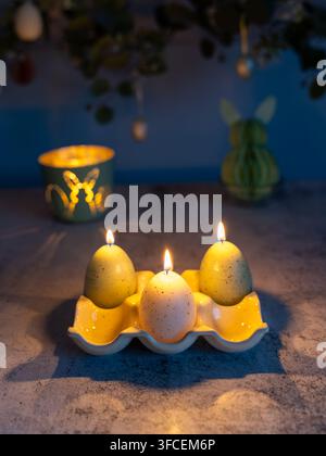 Easter still life featuring lit candles, decorative eggs and spring decorations arranged against a dark background with soft atmospheric lighting Stock Photo