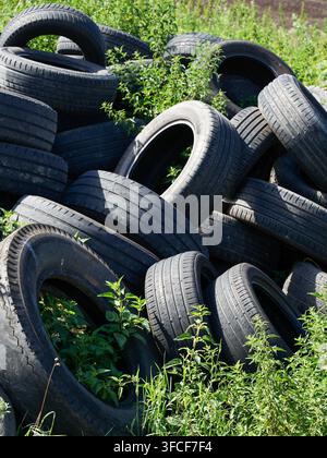 Illegal used car tyre dumping site in nature close-up view Stock Photo