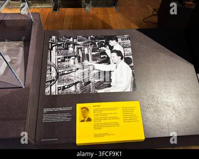 Manchester, UK - July 02, 2026: Historic black and white photograph of technicians assembling the Manchester Baby computer displayed in a museum exhib Stock Photo