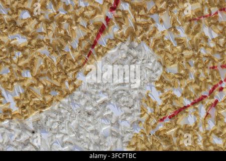 Macro Abstract Texture of Peeling Gold and Red Paint Chips Cracking on White Wall Surface Stock Photo