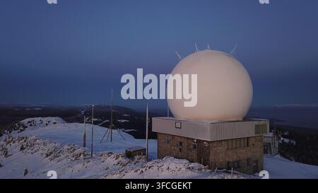 Aerial view of the La Dole radar station with its iconic white radome situated on a snow-covered mountain peak in Gingins, Vaud, Switzerland. Stock Photo