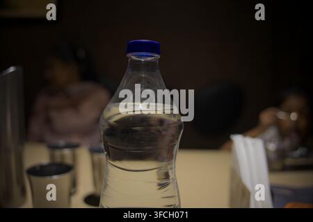 A sealed plastic bottle filled with clean drinking water stands on a restaurant table. Stock Photo