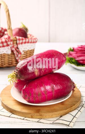 Two large red radishes on a white plate with kitchen background. Stock Photo