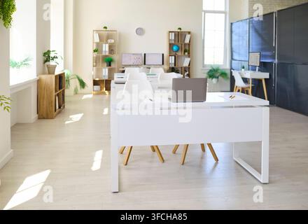 Bright modern classroom interior with white desks, laptops and tall windows Stock Photo
