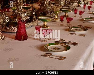 Elegant table setting with porcelain plates, silver cutlery, red goblets, decorative centerpieces Stock Photo