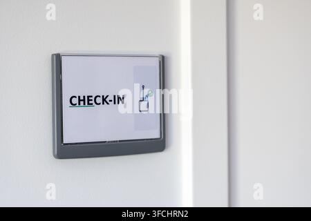 A minimalist sign displaying the word CHECK-IN with a small icon indicating connectivity and a green checkmark for successful status Stock Photo