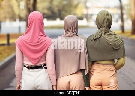 Rear-View Of Three Muslim Ladies Wearing Hijabs Walking Together Outside Stock Photo