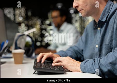 Close up of software developer typing on PC keyboard in startup office, optimizing code for performance and scalability, doing quality assurance. Man Stock Photo