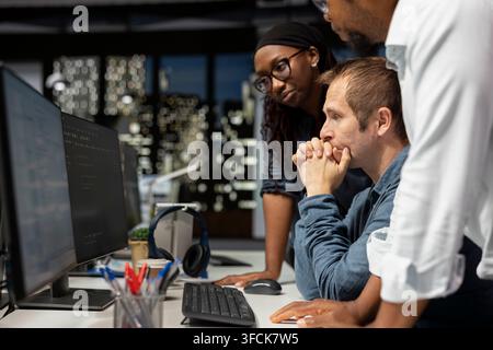 Team of programmers cooperating in AI focused startup, designing, coding and debugging applications. IT specialists at PC desk doing brainstorming, te Stock Photo