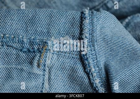 Blue denim fabric presenting a close-up detail of textured textile with a frayed seam Stock Photo