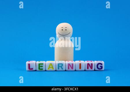 Happy person next to cubes with letters that form the word learning Stock Photo