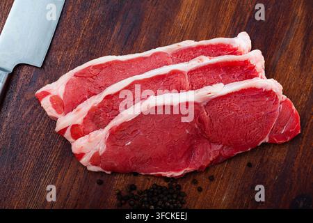 Raw beef entrecotes with peppercorn on wooden surface Stock Photo