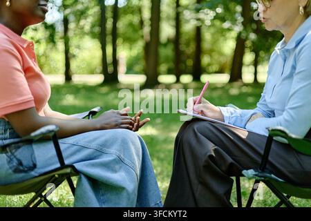 Middle Aged Woman Therapist Consulting Black Woman in Park Stock Photo