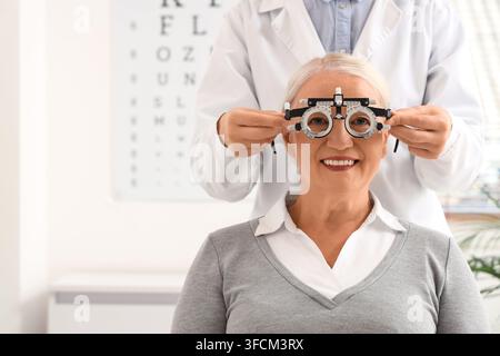 Eye exam and vision care, senior woman having eyesight tested by optometrist with trial frame glasses in clinic for healthy aging and medical checkup Stock Photo