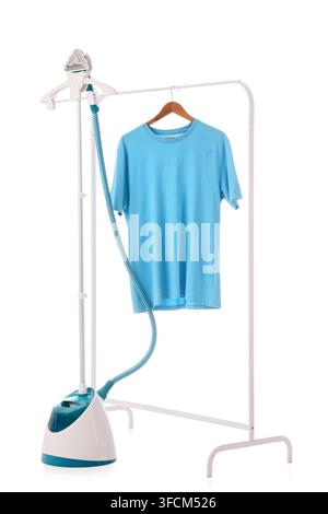Garment care and laundry maintenance, blue t-shirt on a clothes rack with a handheld steam iron for wrinkle removal and fabric refreshing at home Stock Photo
