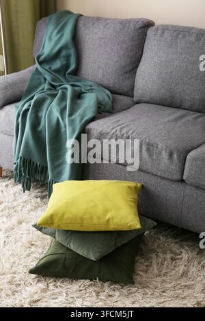 Home comfort and interior design, cozy living room with grey sofa and soft green throw blanket with decorative pillows on a fluffy rug Stock Photo