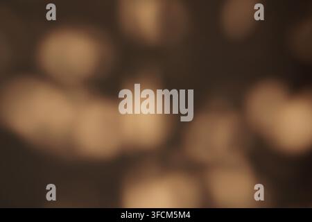 Abstract dark brown background featuring warm golden bokeh lights and soft shadows. Elegant minimalist texture for professional overlays. Stock Photo